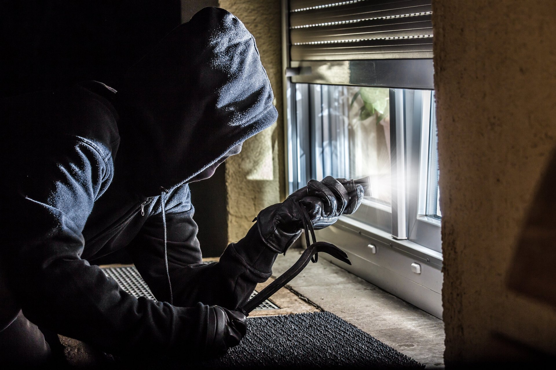 Ein maskierter Einbrecher beabsichtigt in ein Haus einzubrechen, Foto: Rainer Fuhrmann – stock.adobe.com